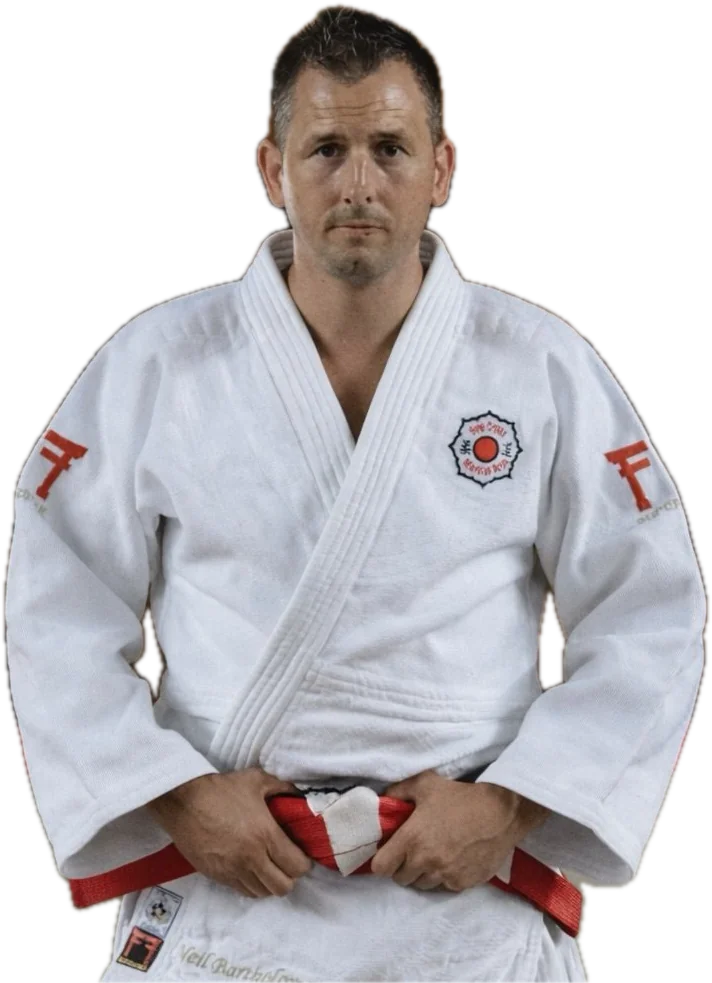 Neil Bartholomew, head coach, in a white judogi with a red and white belt